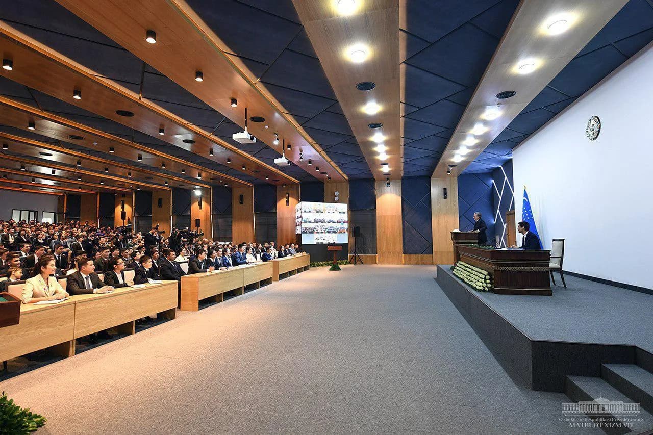 Залда ўтирган ёшлар ва саҳнада маъруза қилаётган Президент