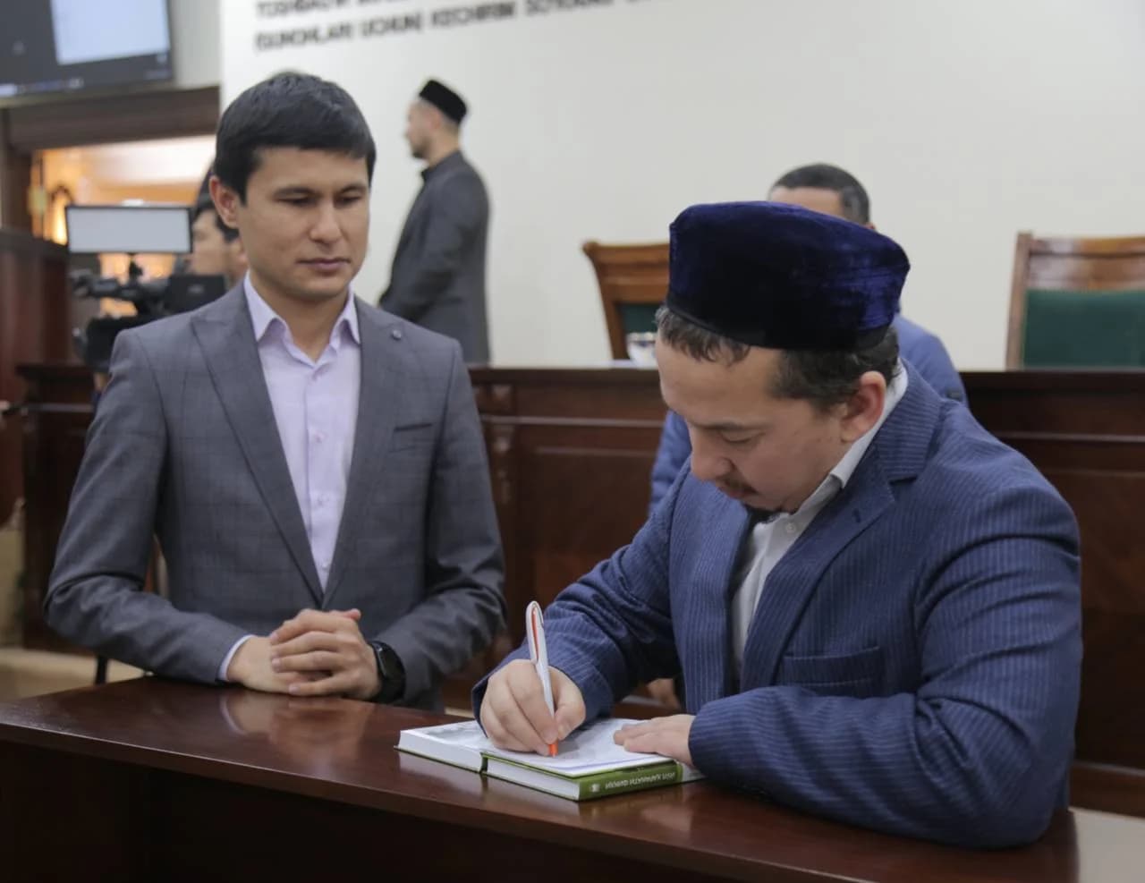 Ҳасанхон Яҳё Абдулмажид китобга дастхат ёзиб бермоқда