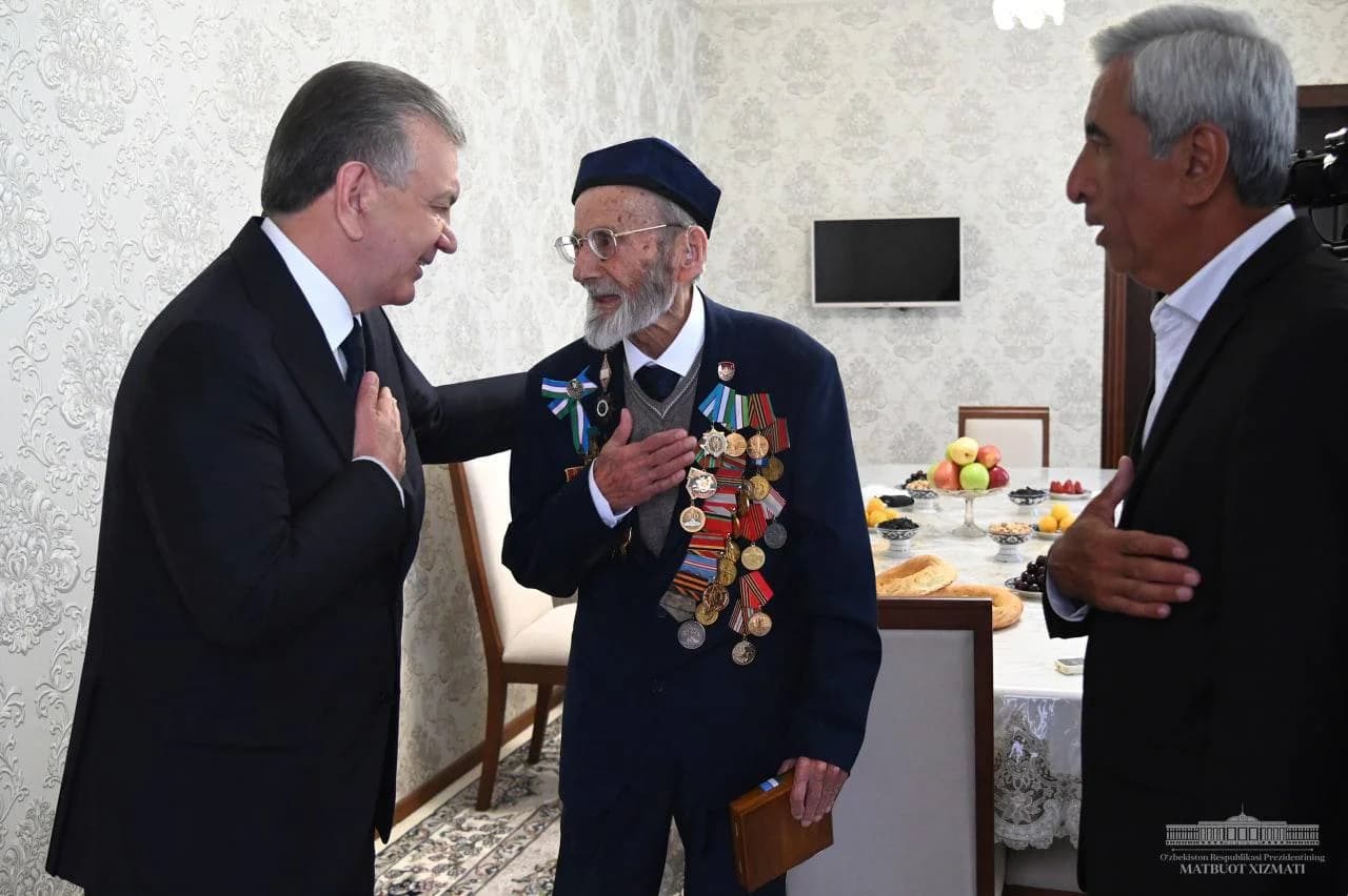 Shavkat Mirziyoyev ko'kragiga orden va medallar taqqan Abbos Appanov bilan suhbatlashmoqda