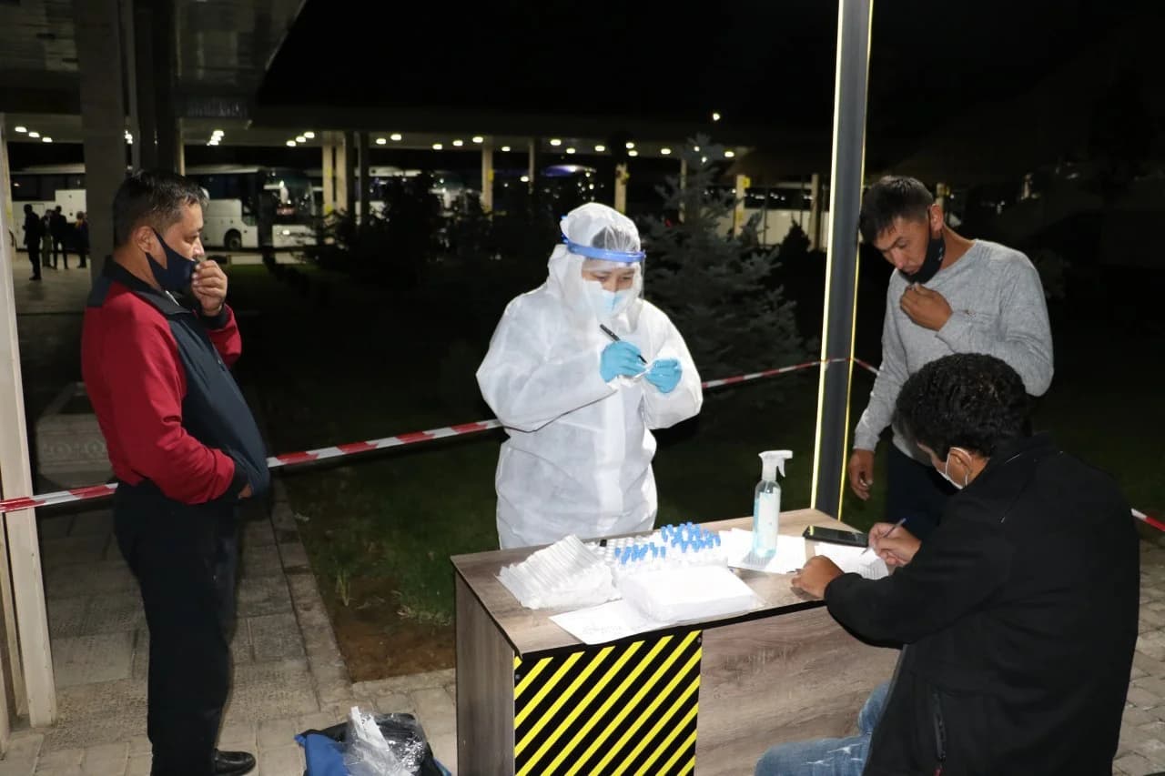 Tungi vaqtda himoya kiyimidagi xodim fuqarolardan tahlil olayotgan jarayon