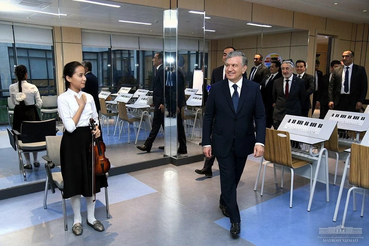 Президент скрипка кўтарган ўқувчи қиз ёнидан ўтиб кетмоқда