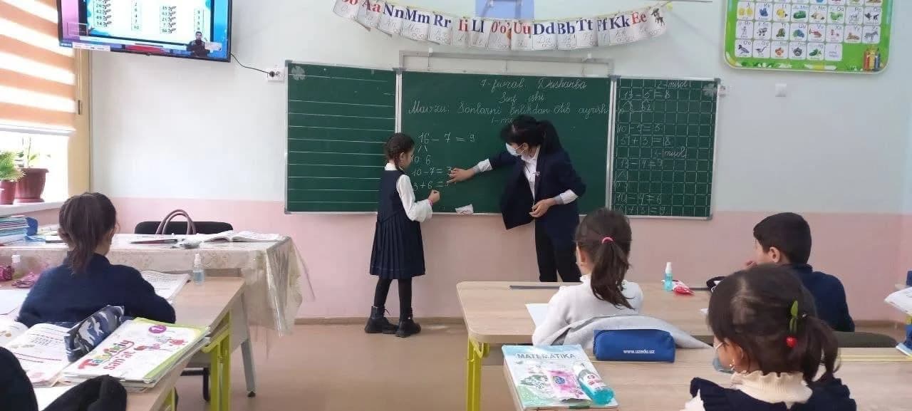 Ўқитувчи ва ўқувчи синф доскаси олдида математика дарсида
