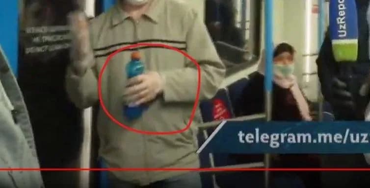Метрода қўлқоп кийган йўловчининг сув идишини ушлаб тургани
