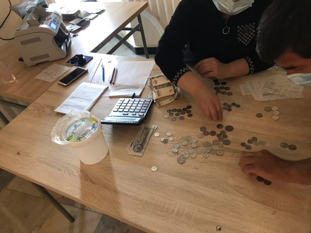 Касса ходимлари болакай олиб келган танга ва купюраларни санамоқда