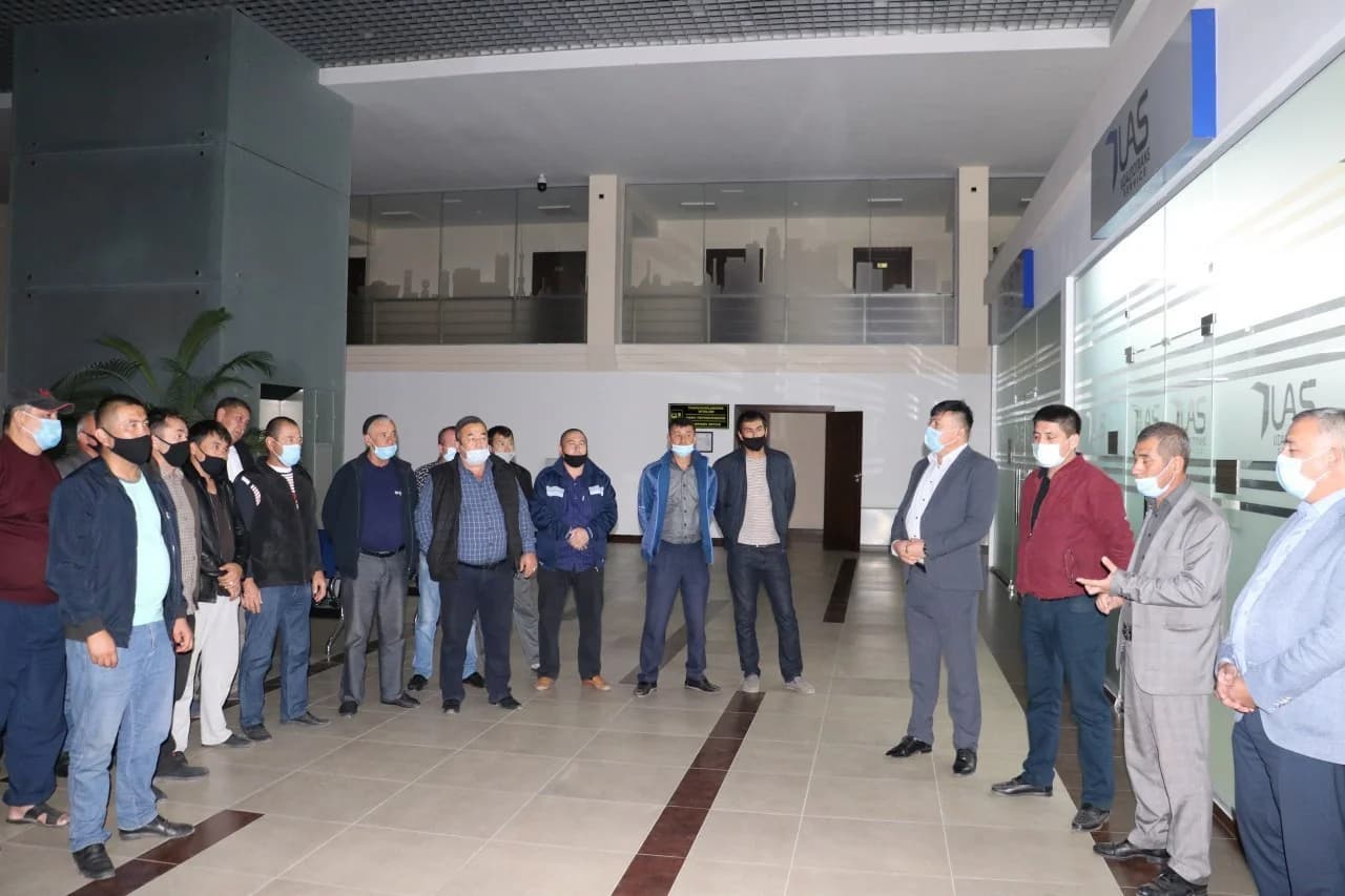 Bino ichida to'plangan bir guruh erkaklar va mas'ul xodimlar suhbati